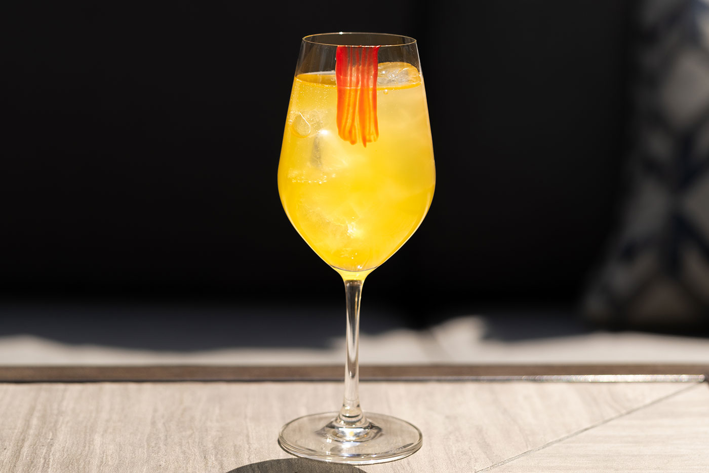 A yellow spritz cocktail in a wine glass